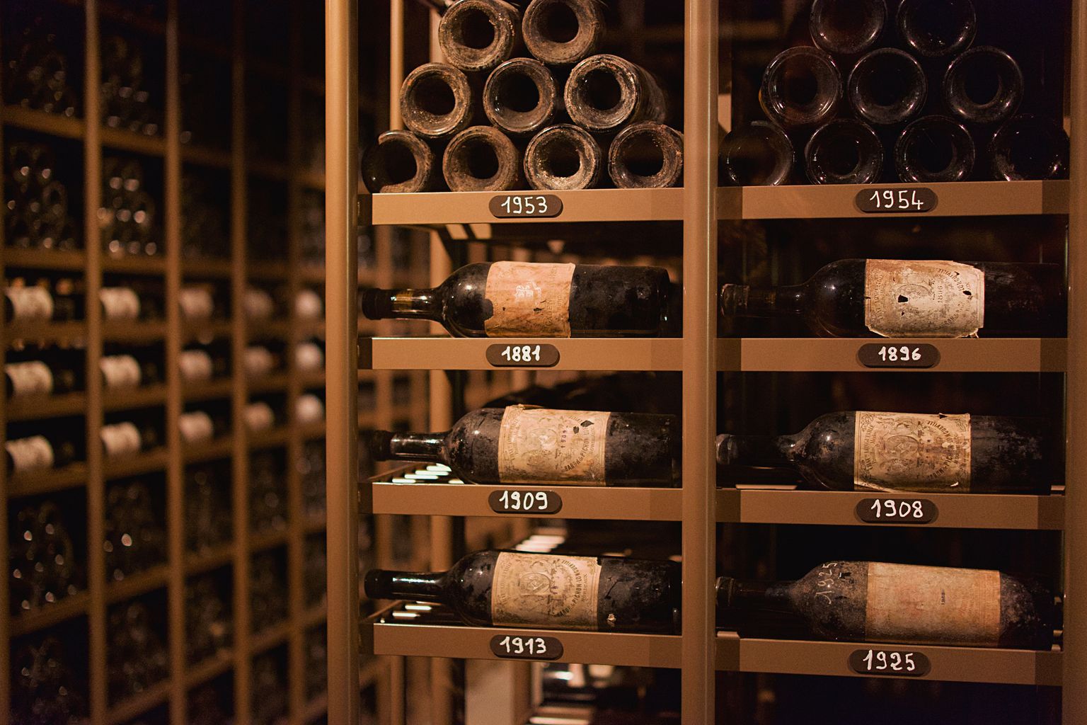 Weinregal mit Flaschen und Fässern in dunkler Holzoptik.
