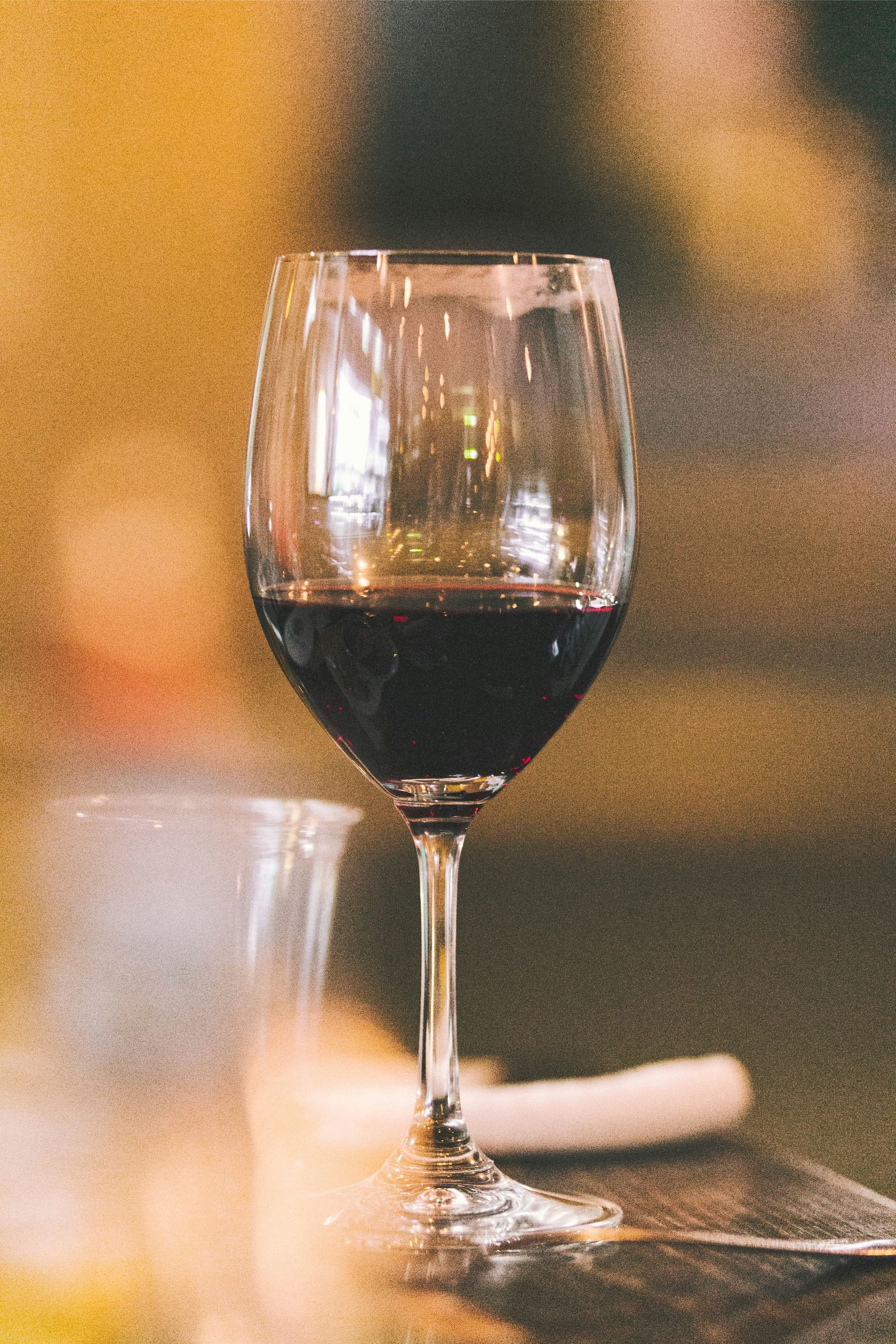 Glas mit dunklem Rotwein auf Tisch, elegant und klar.