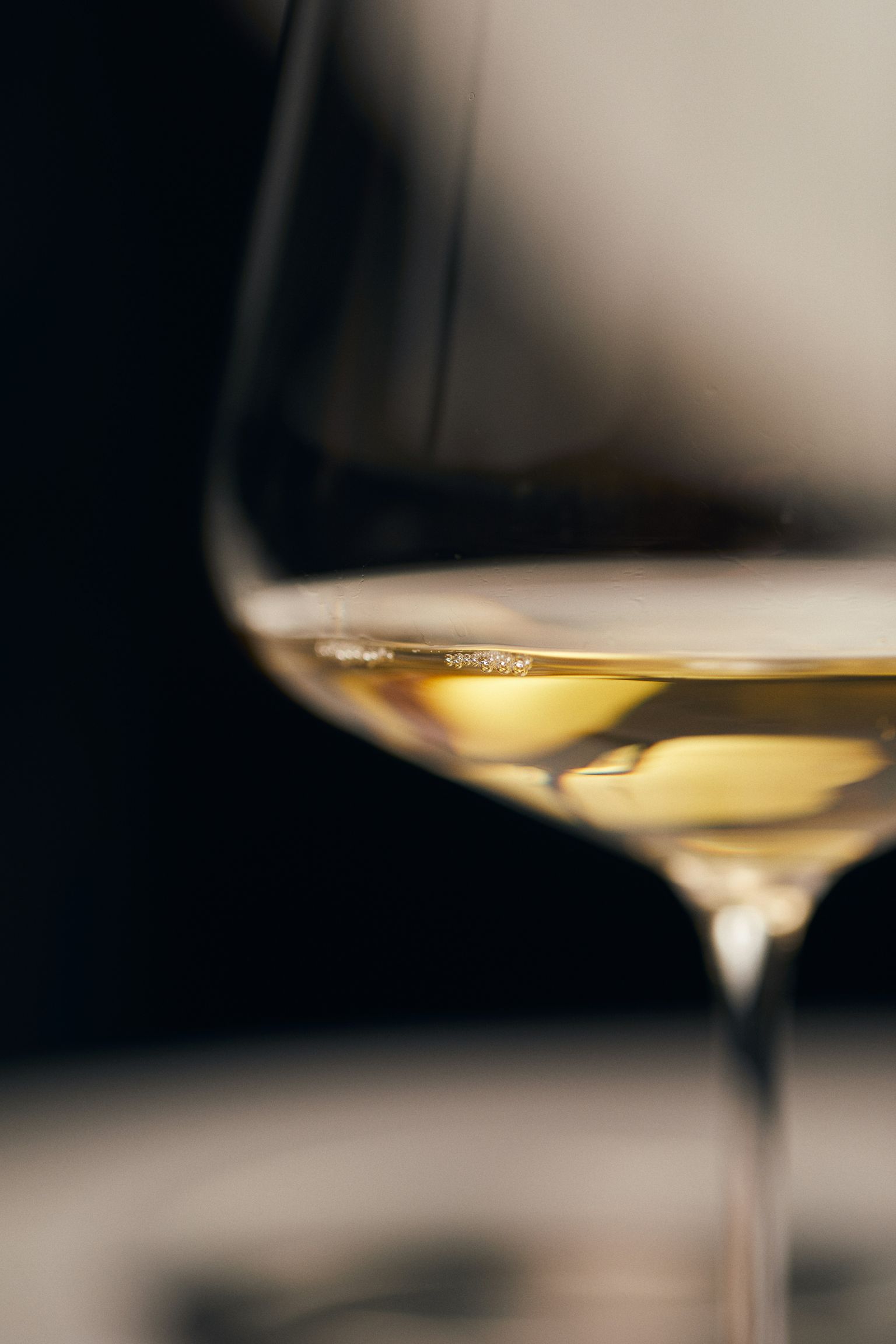Glas mit goldenem Wein, elegant und klar beleuchtet.